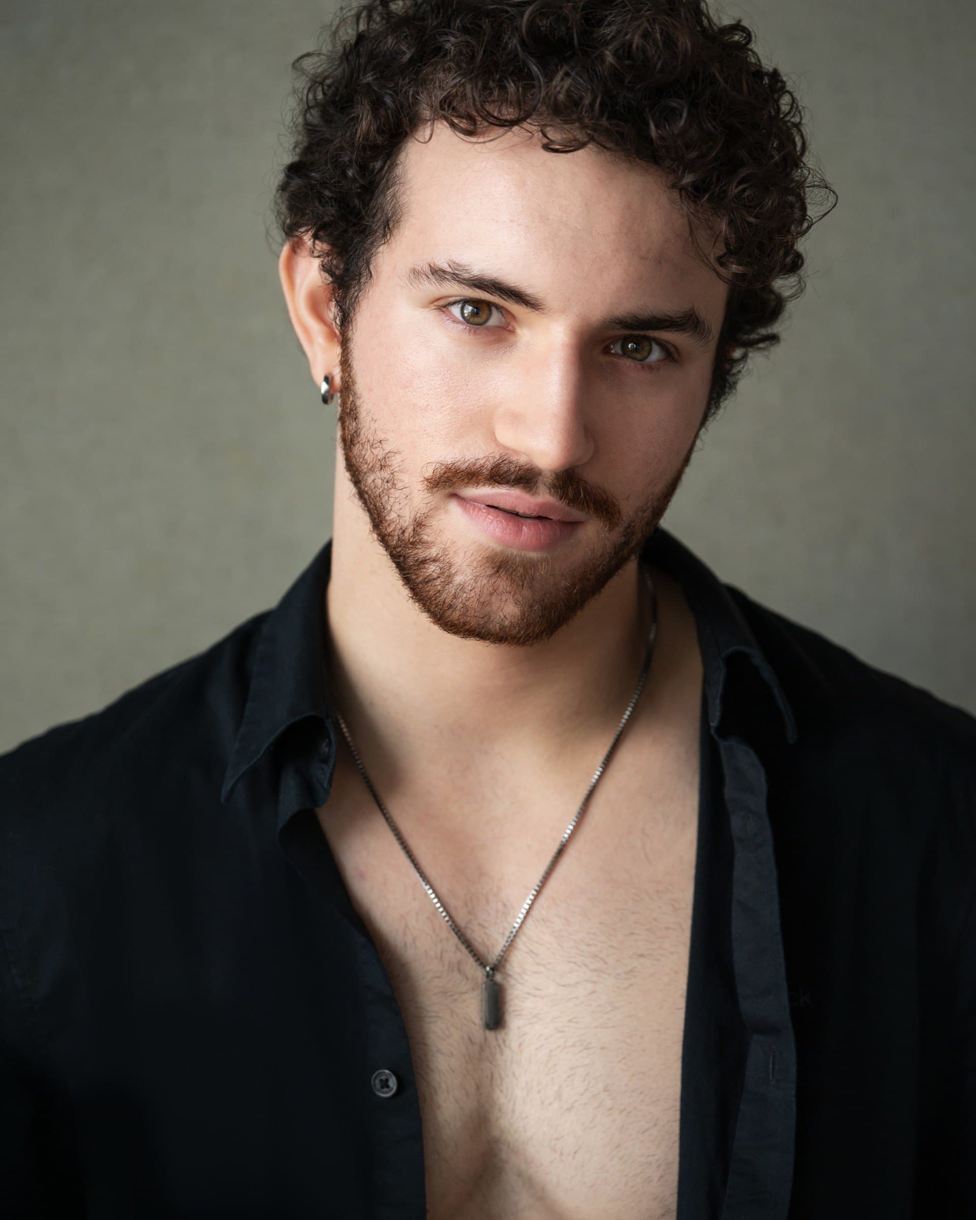 AJ DeAugustine, headshot in an open black shirt